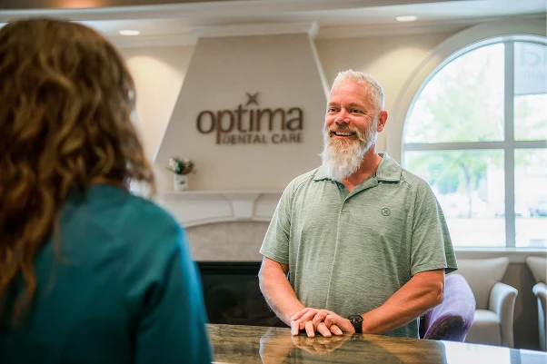 A patient shaking hands with a woman at the front desk