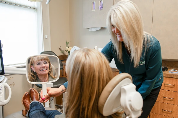 An employee showing a patient their new teeth with a mirror