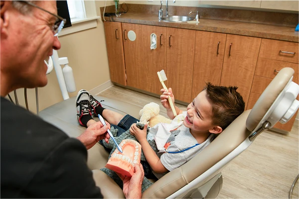 Dr. Johnson showing a patient how to brush their teeth with a model of teeth